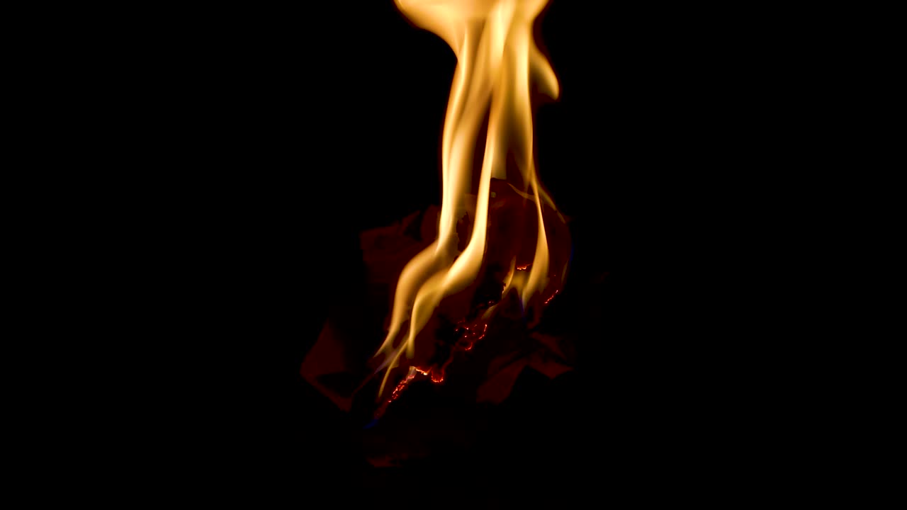 Burning a wrapped white paper on the ground at night close up