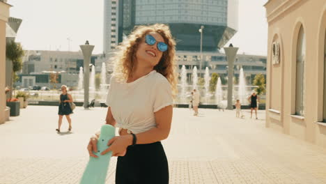 mujer joven con cabello rizado y patineta en la ciudad