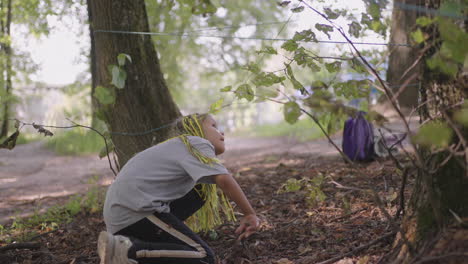 children in a summer camp hike crawls on the ground. training of passing obstacles by crawling on the ground. a girl tumbles in the forest on a camp assignment