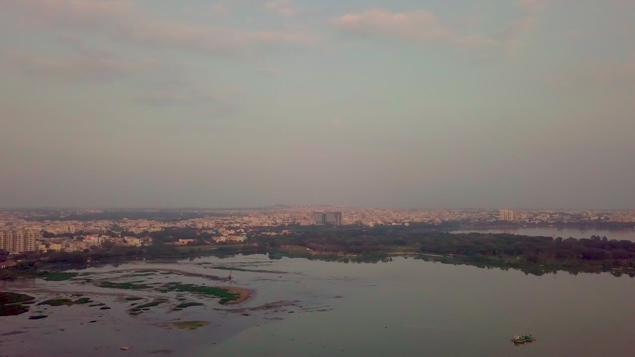 Drone view capturing sunset over a lake in Hyderabad, India with a beautiful cityscape.