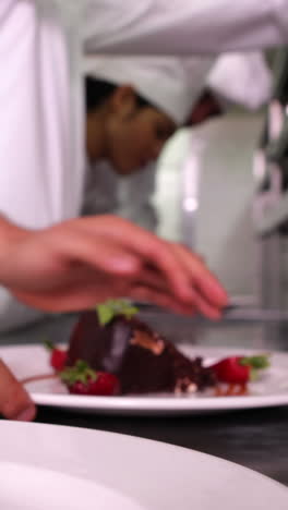 equipo de cocineros adornando platos de postre con hojas de menta y fresas