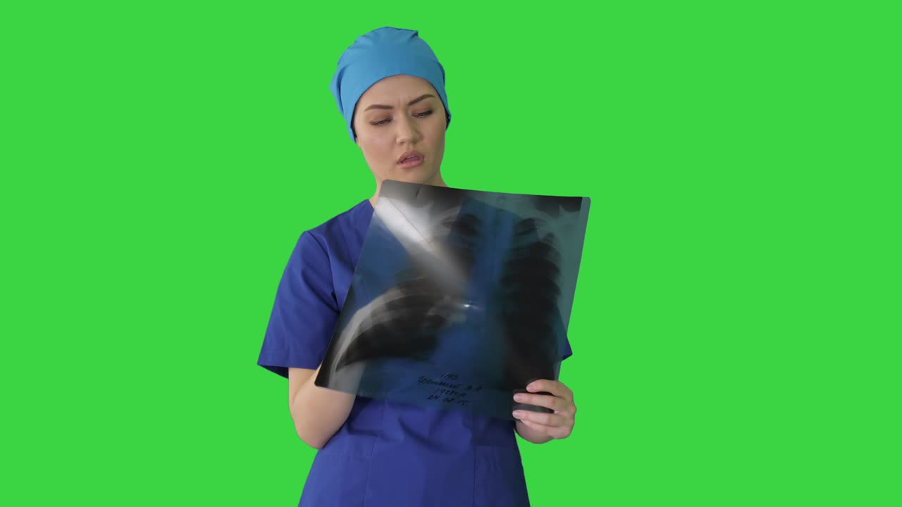 una doctora pensante en uniforme examinando una radiografía de tórax en una pantalla verde, llave de croma