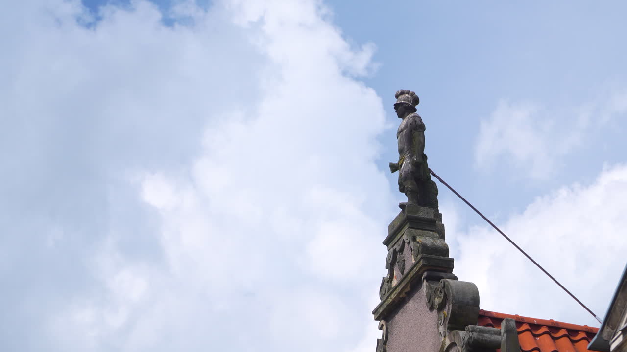 Primo piano di una statua architettonica storica su un tetto contro un cielo azzurro, luminoso e nuvoloso a Danzica