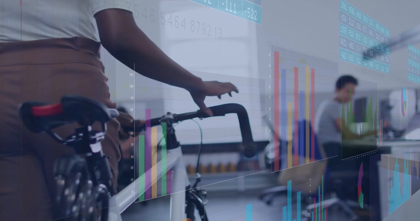 Woman pushing bike through business office to pass desks after shifting grip, gesturing at charts