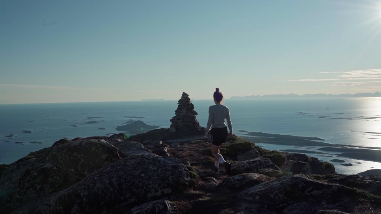 Silhouette Of Woman Walking In Rocky Mountain Overlooking The Ocean In Norway.. - wide panning