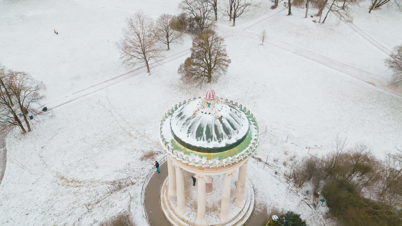 Panoramica delicata con drone sul Monoptero nel Giardino Inglese di Monaco, che cattura una pacifica atmosfera invernale con neve e luce solare tenue