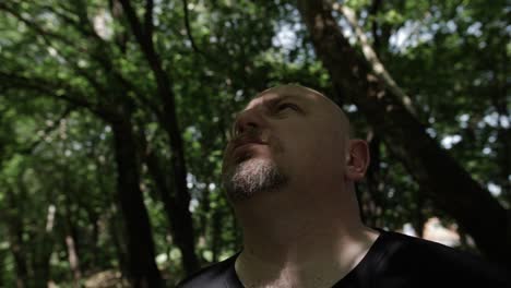 un hombre se para en el bosque mirando el cielo en cámara lenta