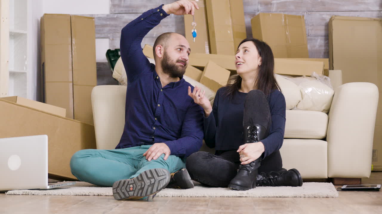 Couple celebrating moving into a new home with keys and boxes