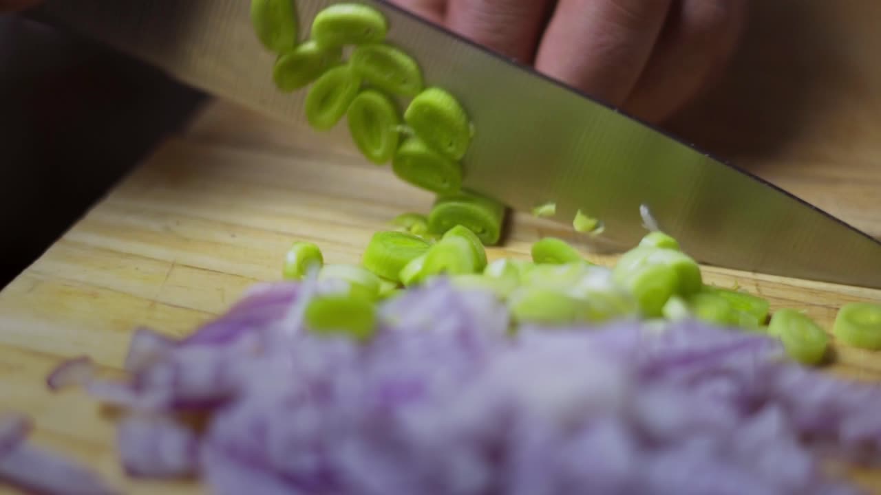 Cook chives and red onion on wooden cutting board