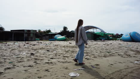 european girl walking on the mui ne beach with round boats in the shore at summer in vietnam