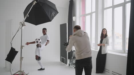 un fotógrafo está tomando fotos de un jugador de fútbol profesional en el estudio para las redes sociales