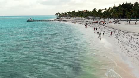 People,-unrecognizable,-walk-on-tropical-beach-after-sunset,-serene-seascape-scene-in-Caribbean-sea,-travel-and-romantic-getaway-at-all-inclusive-resort,-white-sand