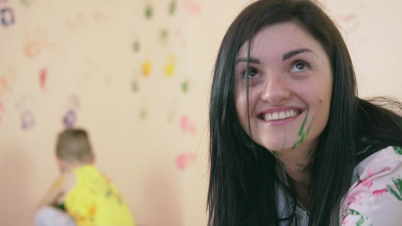 vista de cerca de la sonriente madre feliz con el color en su rostro. feliz niño lindo se está divirtiendo dejando sus huellas en