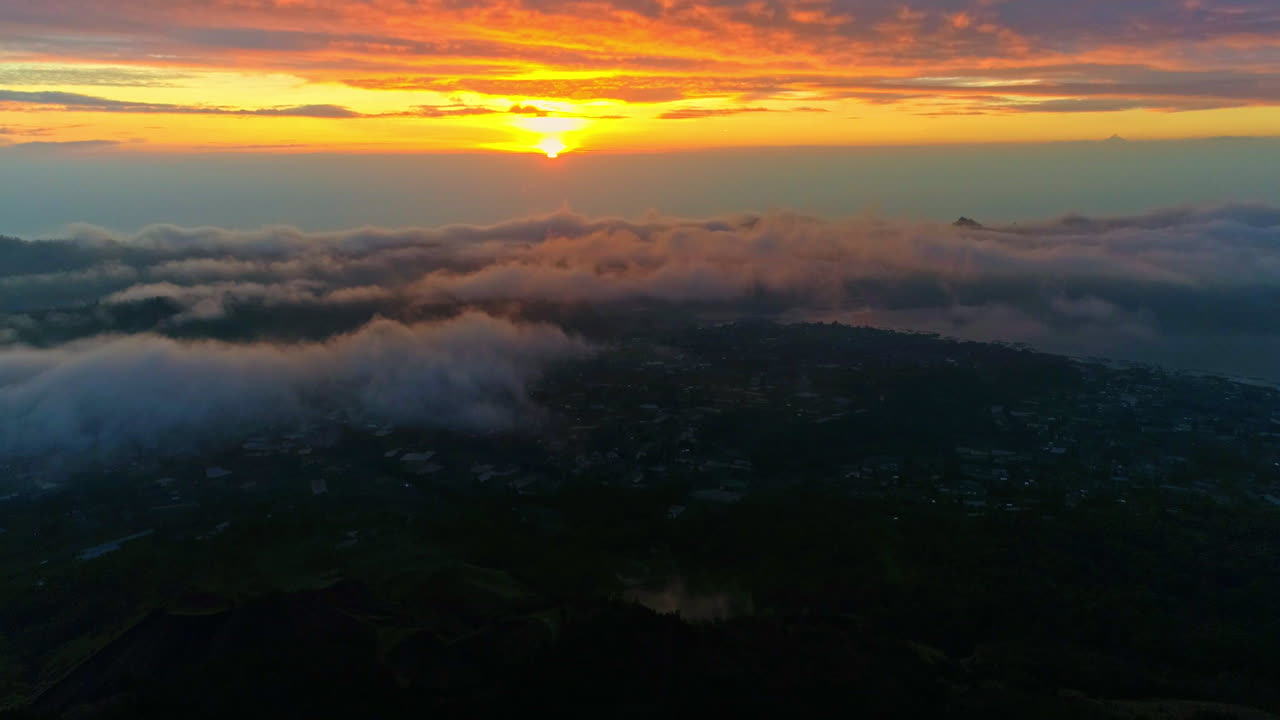 Majestic aerial footage of Mount Batur in Bali during sunrise. Glowing volcanic peaks, morning mist, and golden skies create a stunning scene—ideal for nature, travel, and adventure content