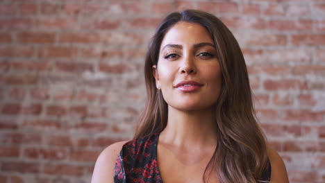 Portrait-Of-Smiling-Hispanic-Woman-Standing-Against-Brick-Wall-In-Coffee-Shop