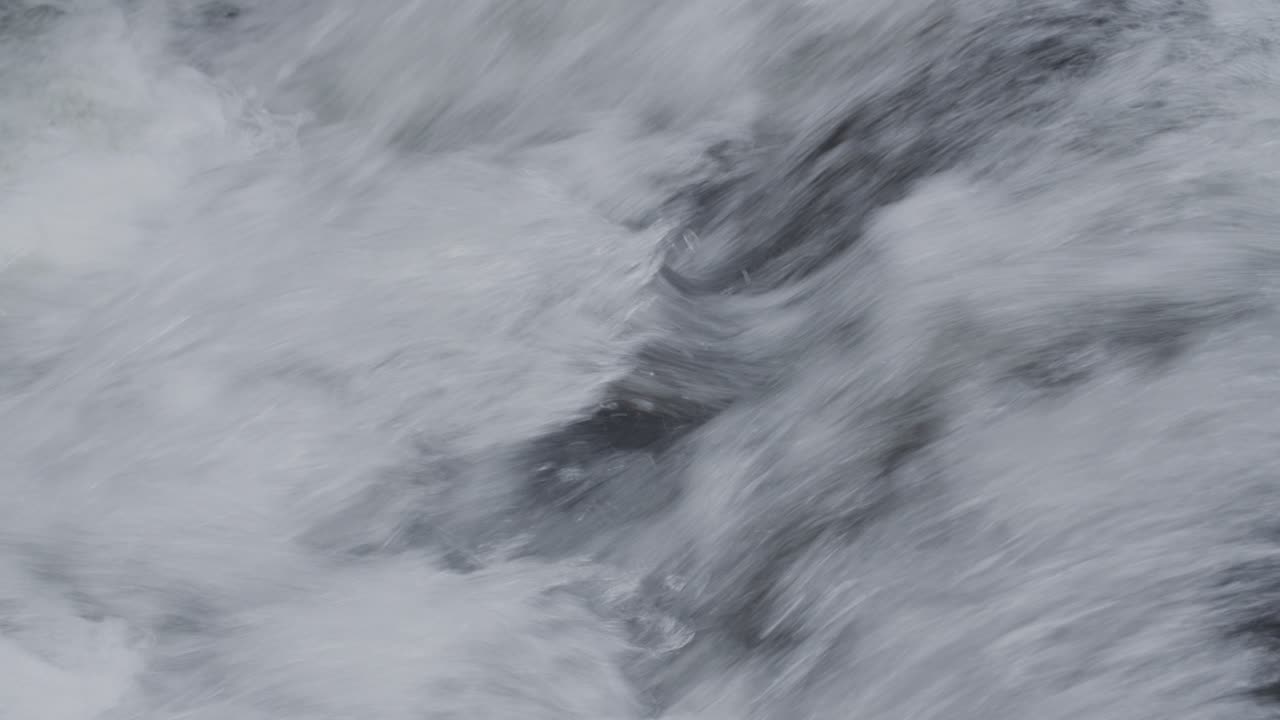 Il rapido scorrere spumeggiante dell'acqua di un fiume.