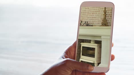 person holding smartphone with modern fireplace interiors displayed on screen