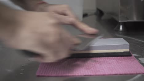 side view close up of cook sharpening a knife using a whetstone 4k