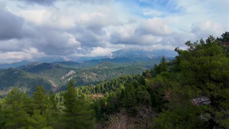 vista aérea sobre un bosque verde con altos picos de montañas y un coche blanco en la carretera de abajo, isla de evia, grecia