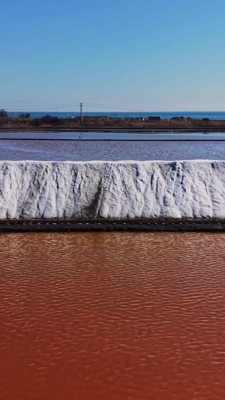 Salt mine with salt piles and water pools under clear skies