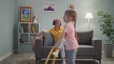 mature lady listens to music little girl jumps with hulahoop