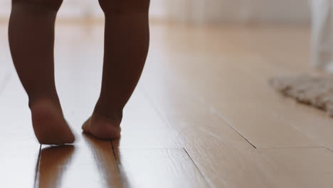 baby learning to walk toddler taking first steps with mother helping infant teaching child at home