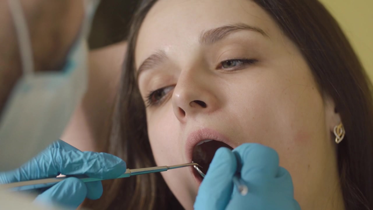 Dentist Examining Young Woman's Teeth in Dental Clinic