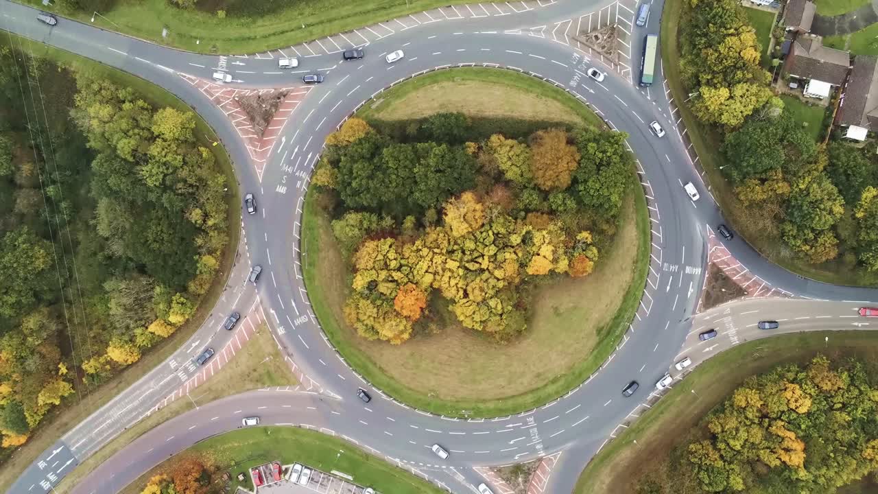 Aerial view above vehicles driving around roundabout intersection urban junction