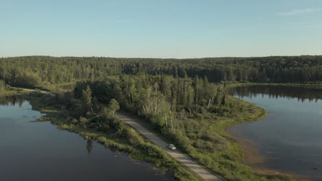 Conducción-De-Camiones-Y-Automóviles-En-La-Carretera-A-Través-De-Lagos-En-El-Bosque-Boreal,-Saskatchewan,-Canadá