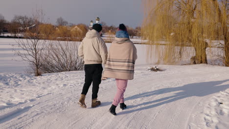 couple walking in snowy village landscape near a church