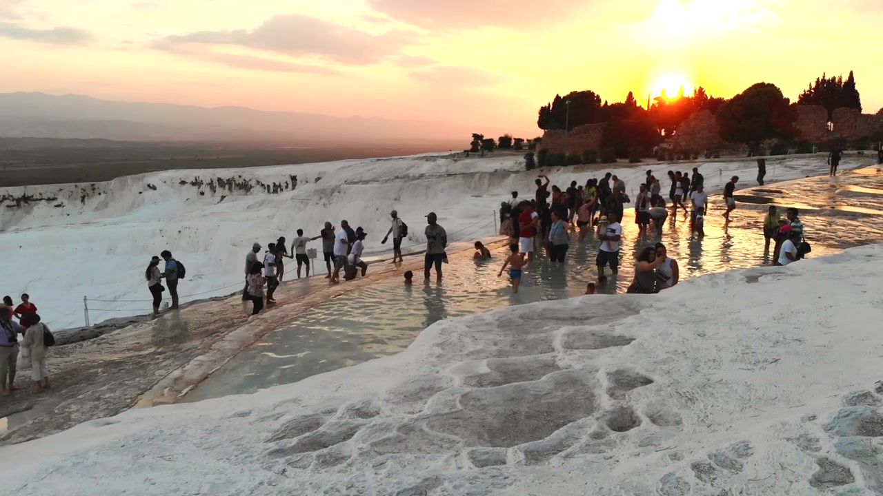 Du khách đi bộ trên các bậc thang đá vôi tại Pamukkale lúc hoàng hôn