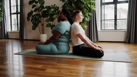 couple practicing seated yoga pose