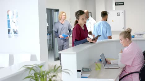 diverse doctors talking to medical receptionist sitting at front desk at hospital, slow motion