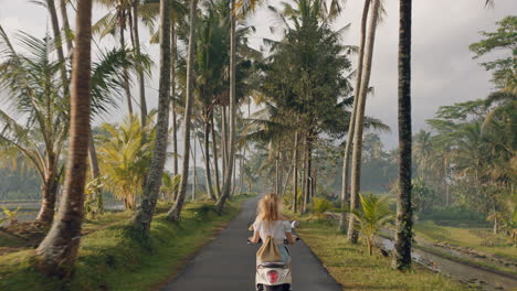 Mujer-Viajera-Montando-Motocicleta-En-Un-Viaje-Por-Carretera-A-Una-Isla-Tropical-Disfrutando-De-Un-Paseo-En-Moto-De-Vacaciones-A-Través-De-Campos-De-Arroz-Y-Palmeras-4k