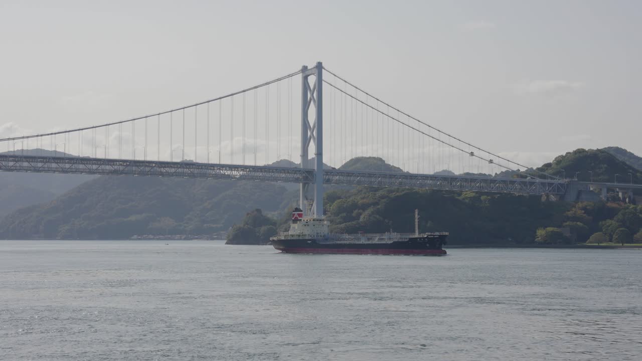 buque de carga en el mar interior de japón, puente shimanami kaido en segundo plano