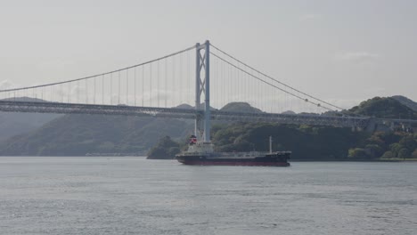 cargo ship in inland sea of japan, shimanami kaido bridge in background