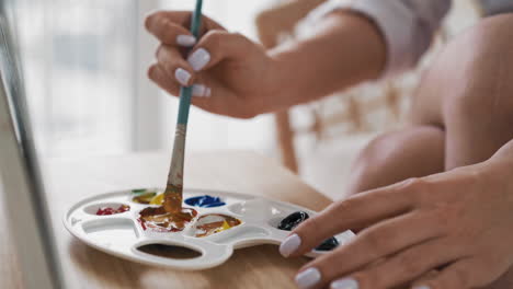 mujer estudiante de arte mezcla pinturas obtiene color naranja en la paleta