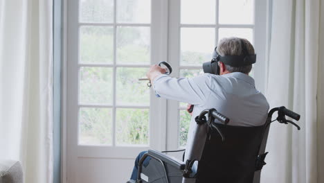 hombre discapacitado en silla de ruedas en casa con auriculares de realidad virtual sosteniendo controladores de juegos