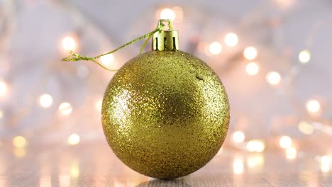 ornamento navideño de brillo dorado brillante con luces parpadeantes detrás