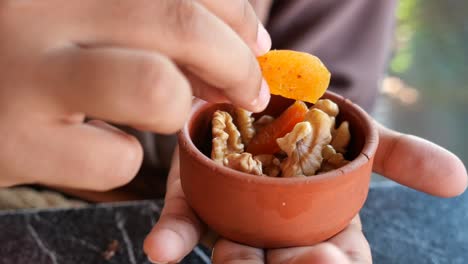 person eating dried apricots and walnuts