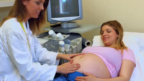 médico presionando las manos en el estómago de una mujer embarazada