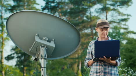 technician sets up a terrestrial satellite dish uses a laptop