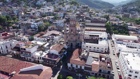 Drohnenflug-Von-Der-Promenade-Von-Puerto-Vallarta-Zur-Kirche-Der-Stadt,-Wobei-Der-Schwerpunkt-Auf-Der-Kirche-Als-Hauptsehenswürdigkeit-Liegt-Und-Die-Stadt-Und-Die-Berge-Im-Hintergrund-Zur-Geltung-Kommen