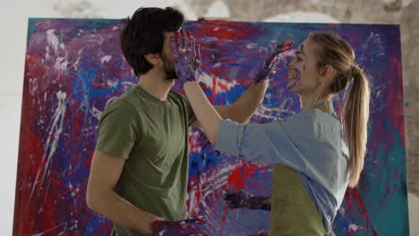 pair in love painting each others faces standing in front large canvas