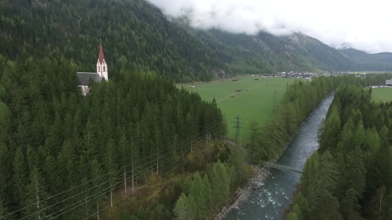 un disparo de un dron de una iglesia cerca de un río por los alpes