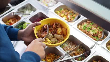 person selecting food from a self-service buffet line