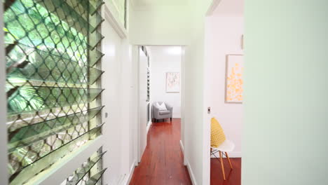 modern home interior with wooden flooring dolly along hallway to master bedroom with large jalouise window panels