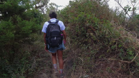 POV-following-woman-hiking-with-backpack-on-jungle-mountain-trail