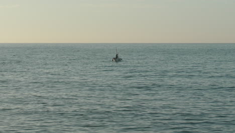 Ein-Einsames-Fischerboot-Schwimmt-Während-Der-Goldenen-Stunde-Im-Meerwasser