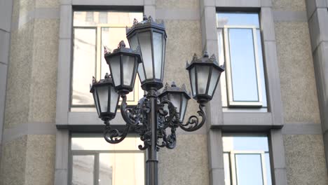 a black street lamp with five lights in front of a modern building